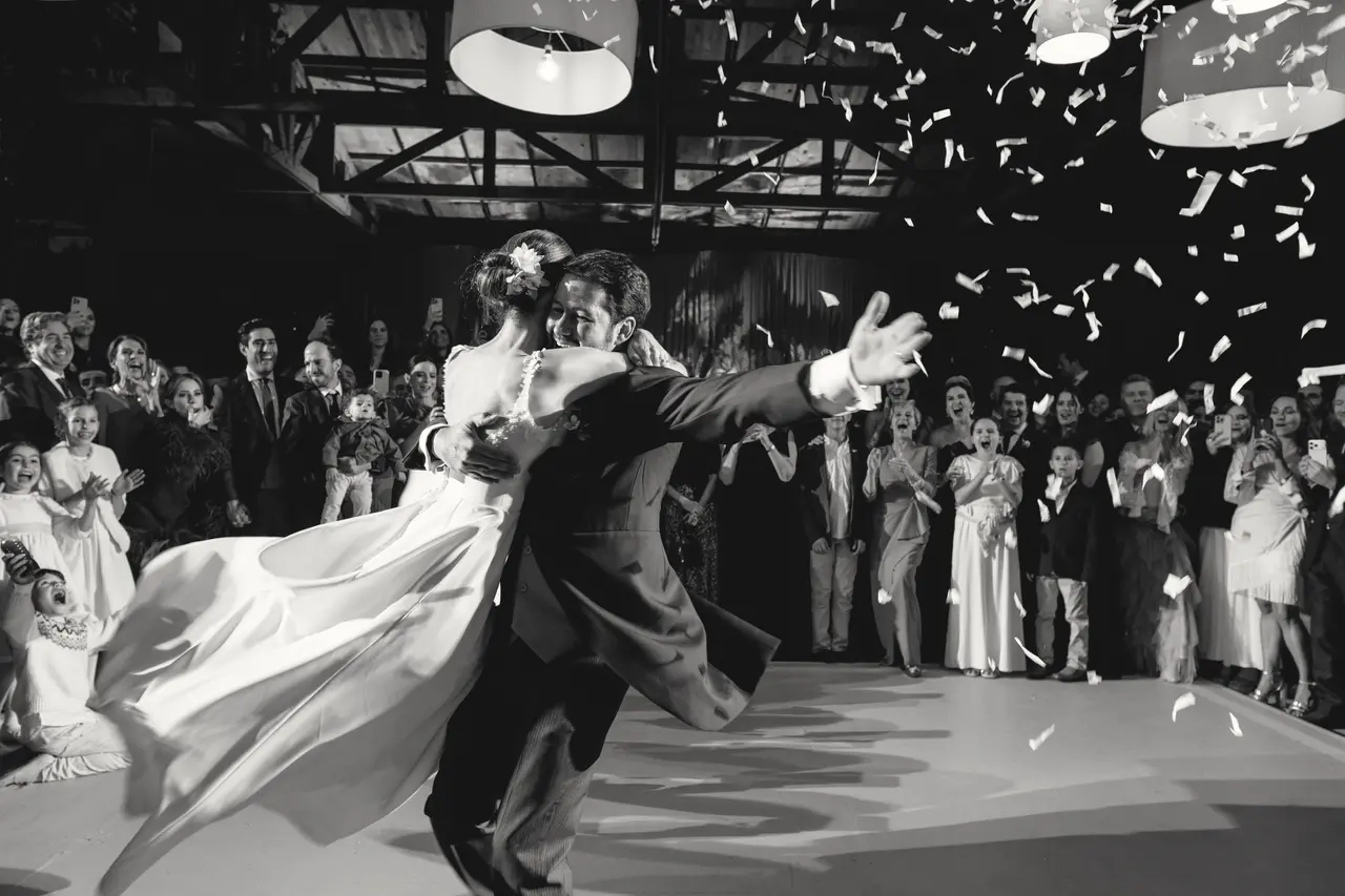 Los novios bailan bajo el confeti con los invitados en corro